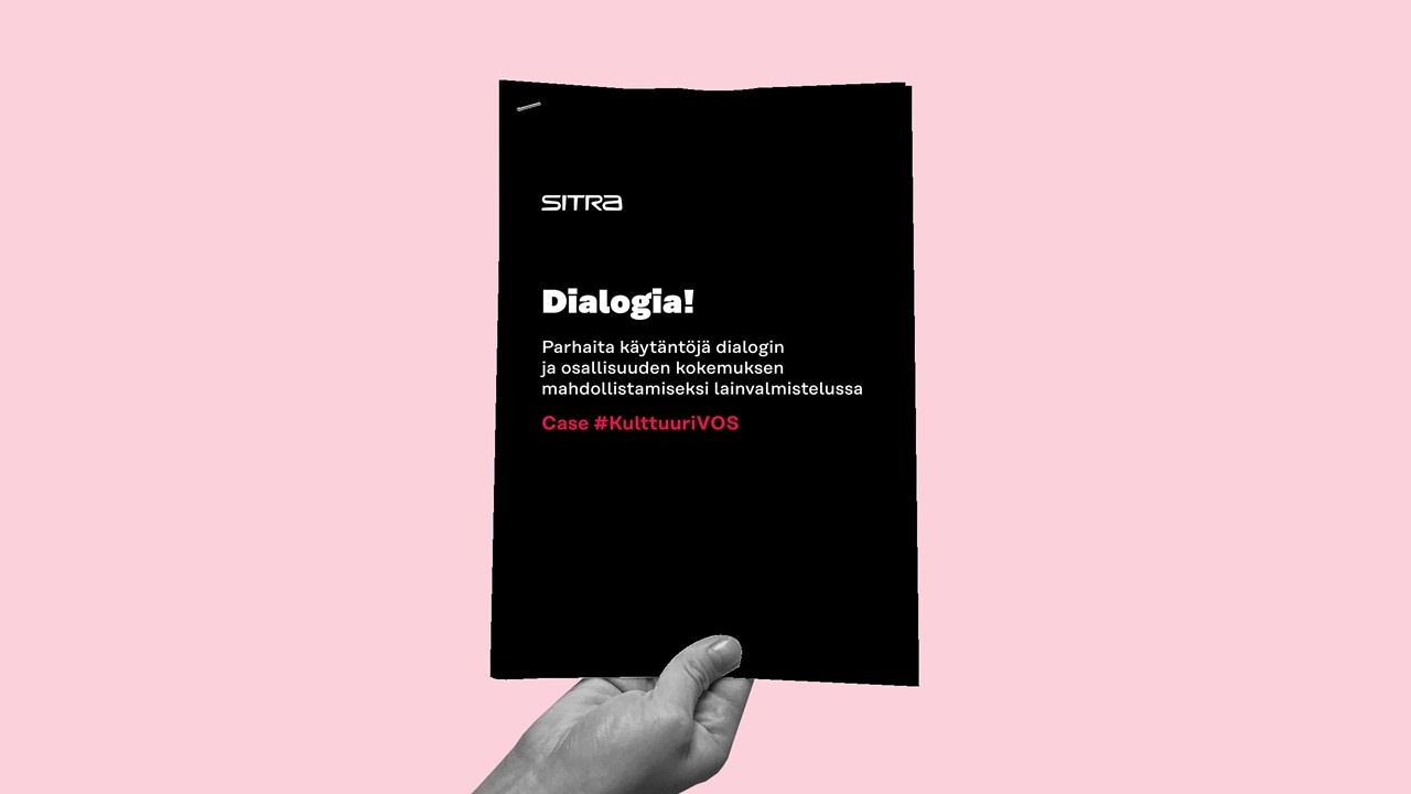 Kädessä on musta vihkonen vaaleanpunaisella taustalla. Kirjasessa lukee: Dialogia! Parhaita käytäntöjä dialogin ja osallisuuden kokemuksen mahdollistamiseksi lainvalmistelussa. Asia #KulttuuriVOS.