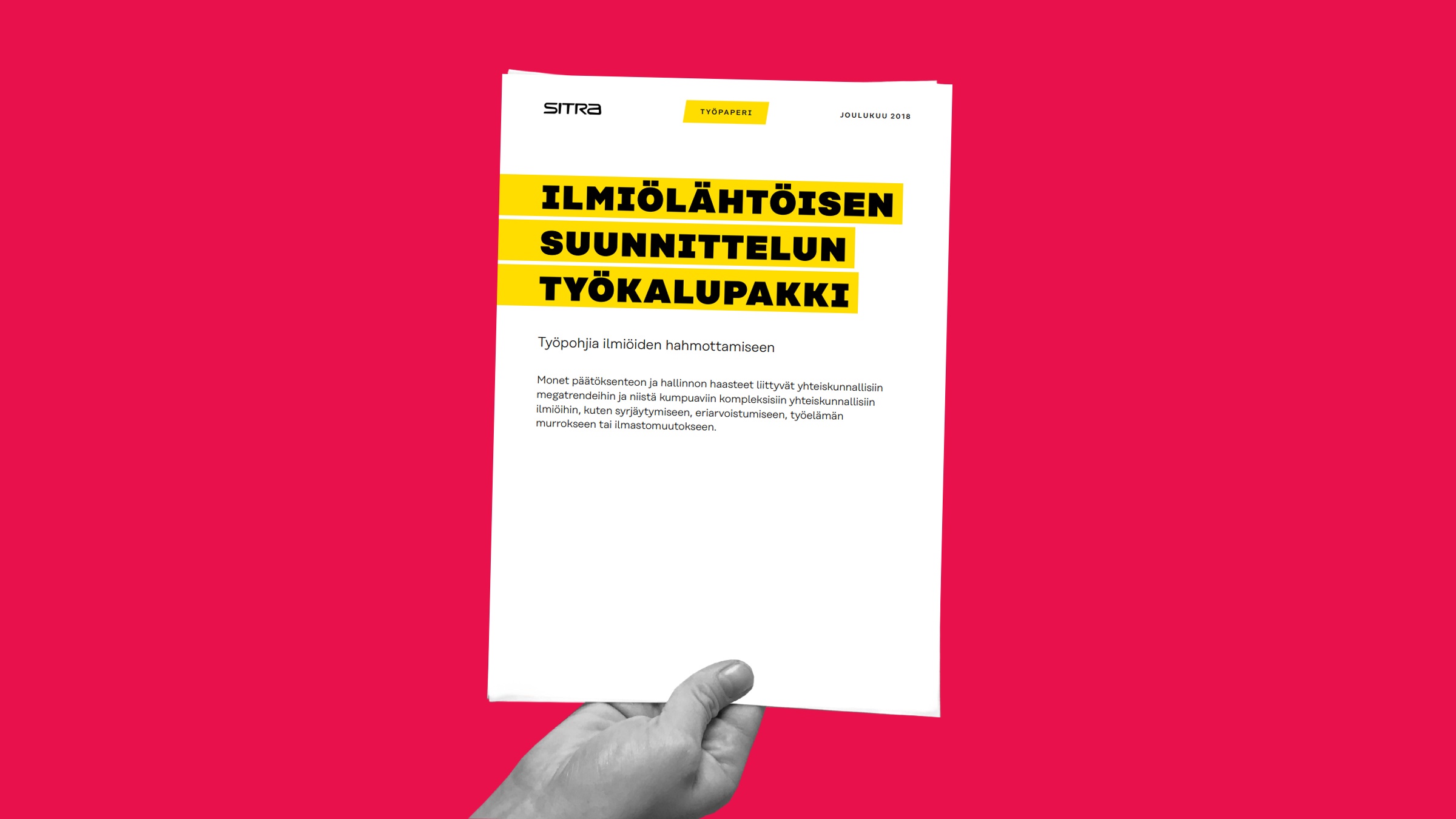 Kädessä on kirkkaan vaaleanpunaisella taustalla asiakirja, jonka otsikkona on ILMIÖLÄHTÖISEN SUUNNITTELUN TYÖKALUPAKKI. Asiakirjan otsikossa on SITRAn logo ja hieman suomenkielistä tekstiä.