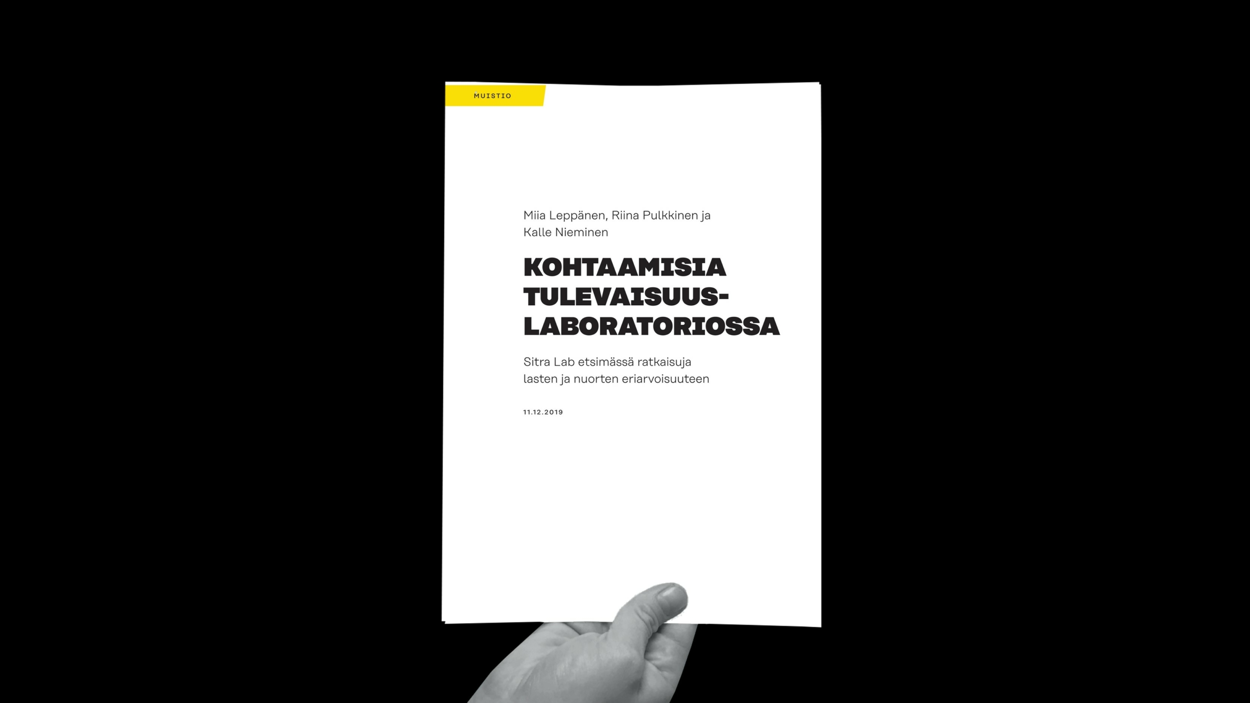 Käsi nostaa ylös kirjasen, jossa on valkoinen kansi mustaa taustaa vasten. Kannessa on musta suomenkielinen teksti ja vasemmassa yläkulmassa keltainen laatikko, jossa lukee MAKUPALA.