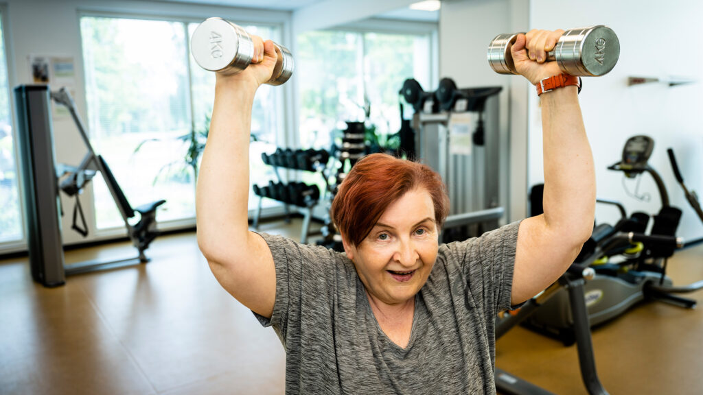 Ulla Koskinen nostaa käsipainoja kuntosalilla.