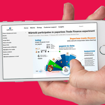 Hand holding a mobile phone with a screenshot of Wärtsilä's press release on the topic of this article.