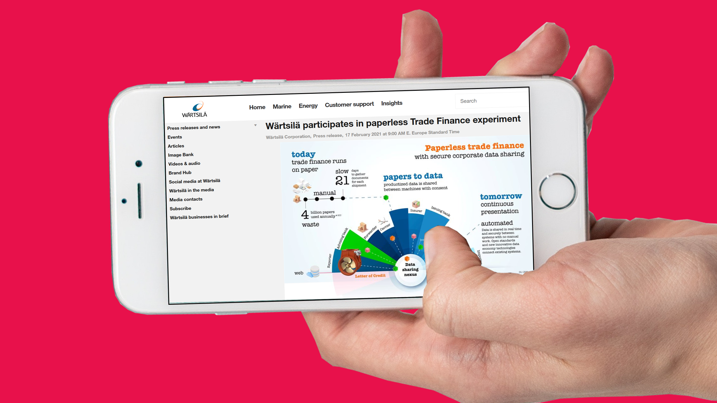 Hand holding a mobile phone with a screenshot of Wärtsilä's press release on the topic of this article.